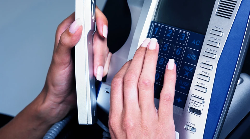 Persona che utilizza un telefono fisso aziendale a rappresentare la linea fissa base per le imprese con servizi di avviso, trasferimento chiamata e conversazione multipla