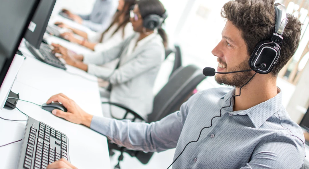 Operatore telefonico al lavoro davanti al computer assiste i clienti tramite il numero verde prepagato di TIM Business pensato per imprese e aziende