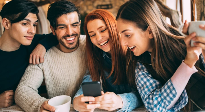 Gruppo di amici sorridenti in un bar mentre utilizzano il wi-fi gratuito di TIM Business per socializzare e condividere contenuti sui social