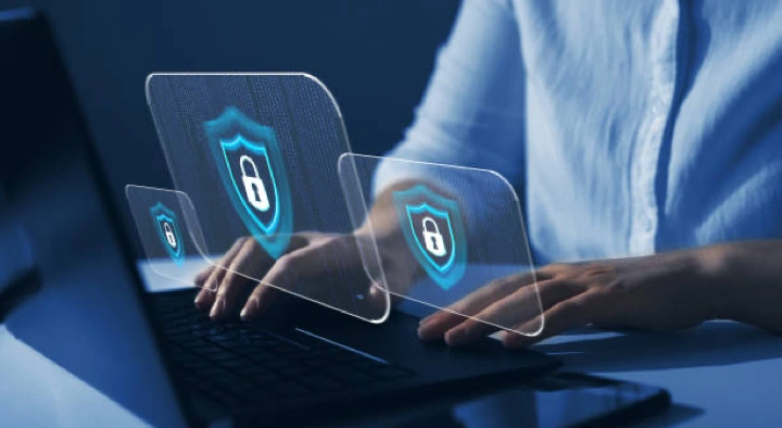 Uomo al lavoro davanti a un laptop con icone di sicurezza digitale, che evidenziano la protezione dei dati aziendali con password sicure e diverse