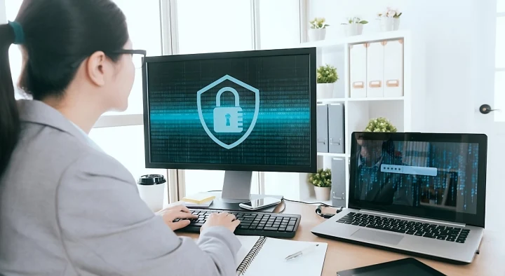 Donna al computer che monitora la sicurezza della rete, evidenziando il servizio Skillo Sentinel di TIM Business per la gestione proattiva dei device connessi
