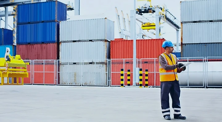 Lavoratore di un cantiere marittimo mentre utilizza un dispositivo IoT per la geolocalizzazione di container e prodotti tramite dispositivo GPS
